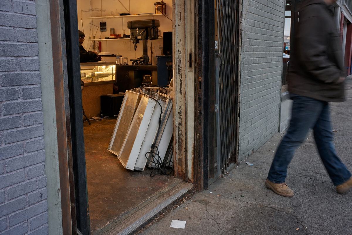 A Jackson Avenue pawn shop with the door open to a scarred drill press and a row of used grow lights, seen in late afternoon light.