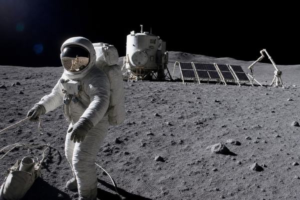 Digital press photograph captured on the Moon near the Malapert plateau in 2005: a European astronaut in a slightly dusted white EVA suit stands three-quarters turned, left glove reaching toward a tether line, visor reflecting the low Sun and the edge of a solar array; behind her, a compact cylindrical habitat module with an offset airlock, a bank of tilted solar panels on aluminum frames, and a slender robotic arm parked to the right; boot tracks curve across gritty regolith; small cable loops and a tool bag rest near a footpad; deep black sky with no stars; photographed with a ruggedized DSLR in an EVA housing (24mm equivalent lens), high-contrast highlights with faint sensor noise in shadowed regolith, mild lens flare and slight horizon roll; off-center composition with the astronaut in the left third; no text, logos, flags, or markings visible.