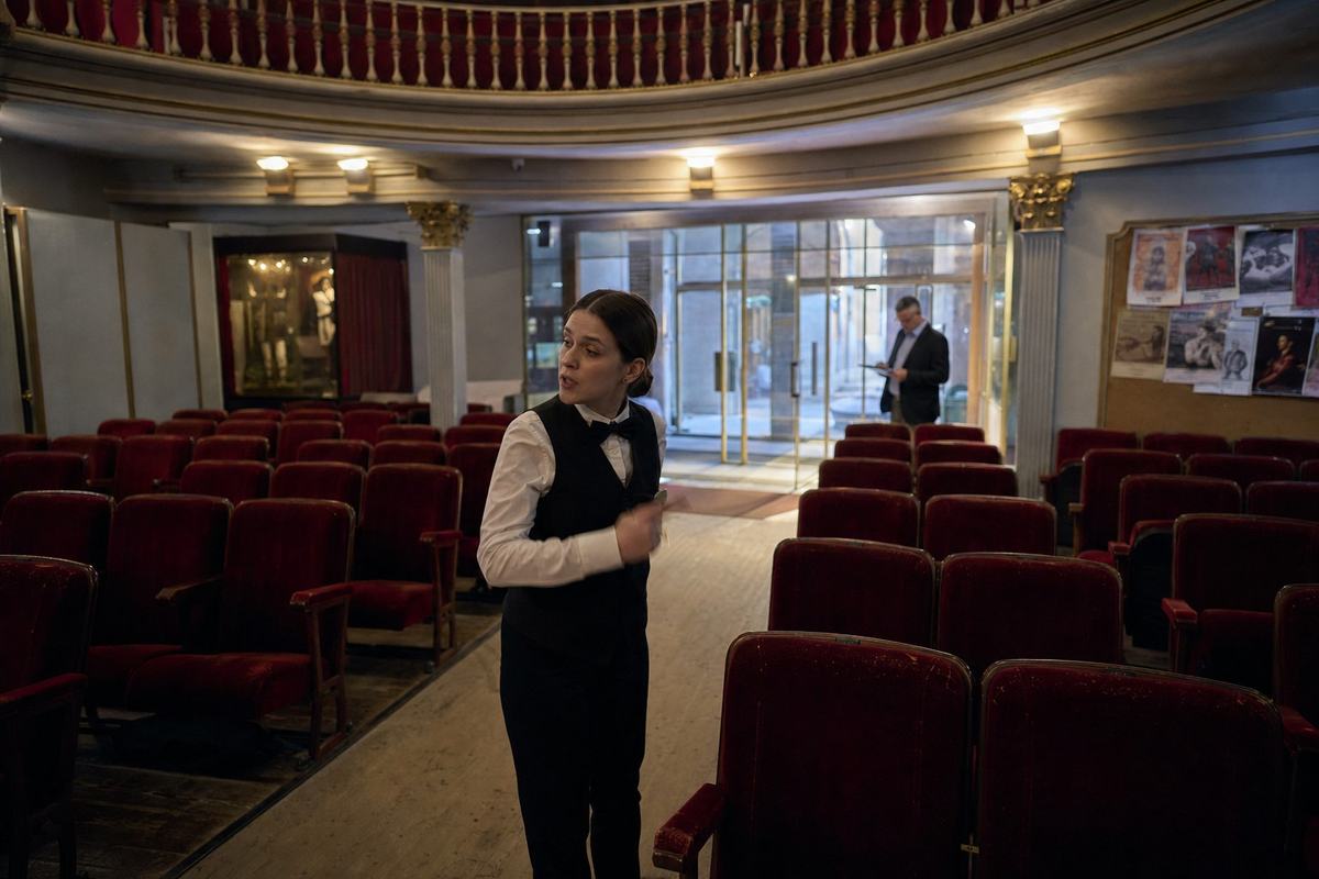 Butacas rojas casi vacías y un ujier solo bajo la galería del Teatro de la Compañía.