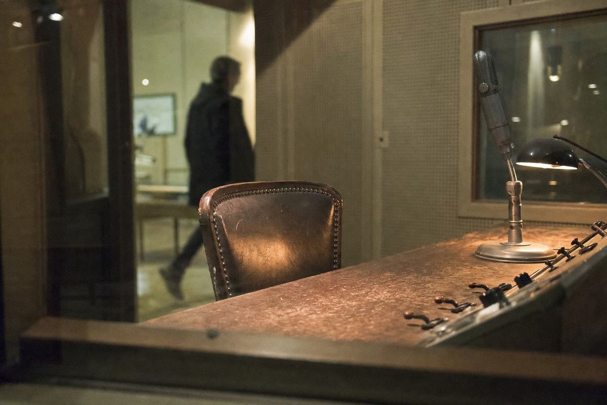 Studio radio reconstitué aux Archives nationales, chaise vide sous une lampe et micros à long col.