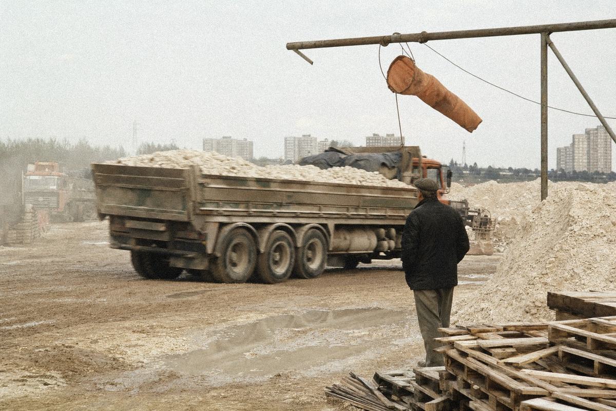 Melton chalk quarry yard with chalk dust and a loaded lorry, windsock limp on the gantry.