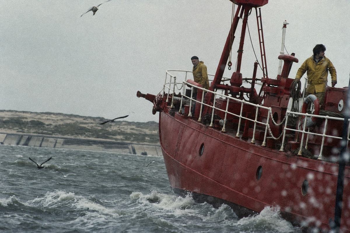 The Spurn lightship on a grey swell off the peninsula, crew on deck under low cloud.