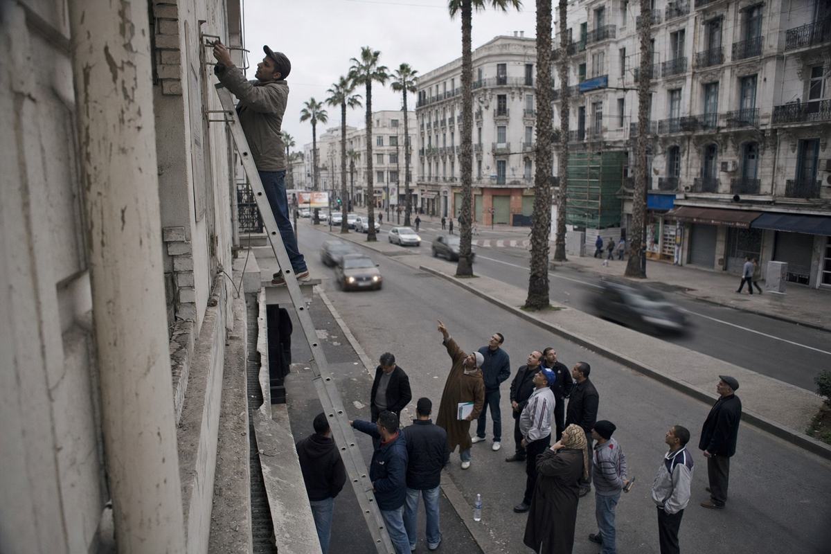 Large sur le boulevard d’Anfa: une échelle appuyée à un immeuble des années 1930, une petite foule s’attroupe au pied, ciel couvert.