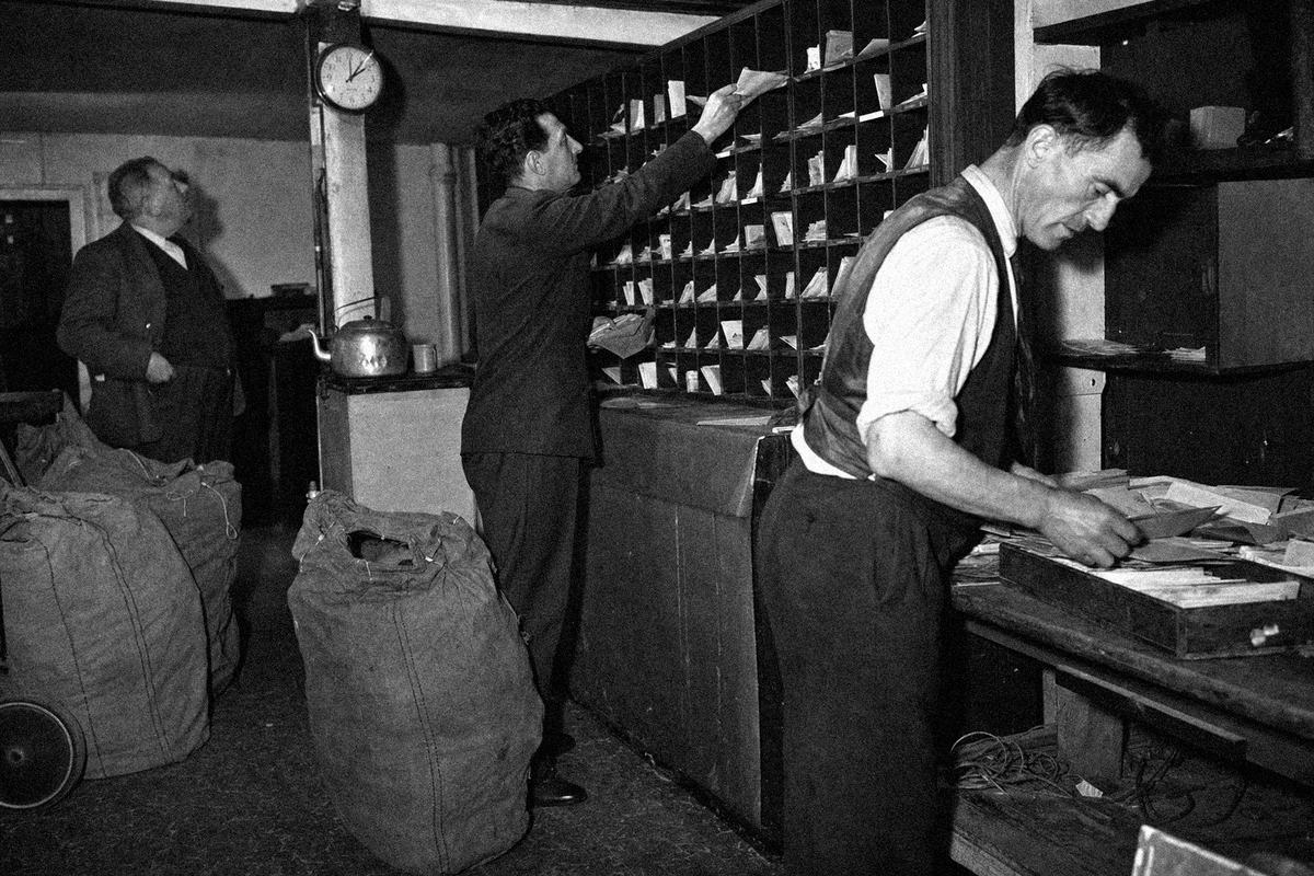 Clerks hand‑sorting mail sacks and envelopes in the Castlebar sorting room.