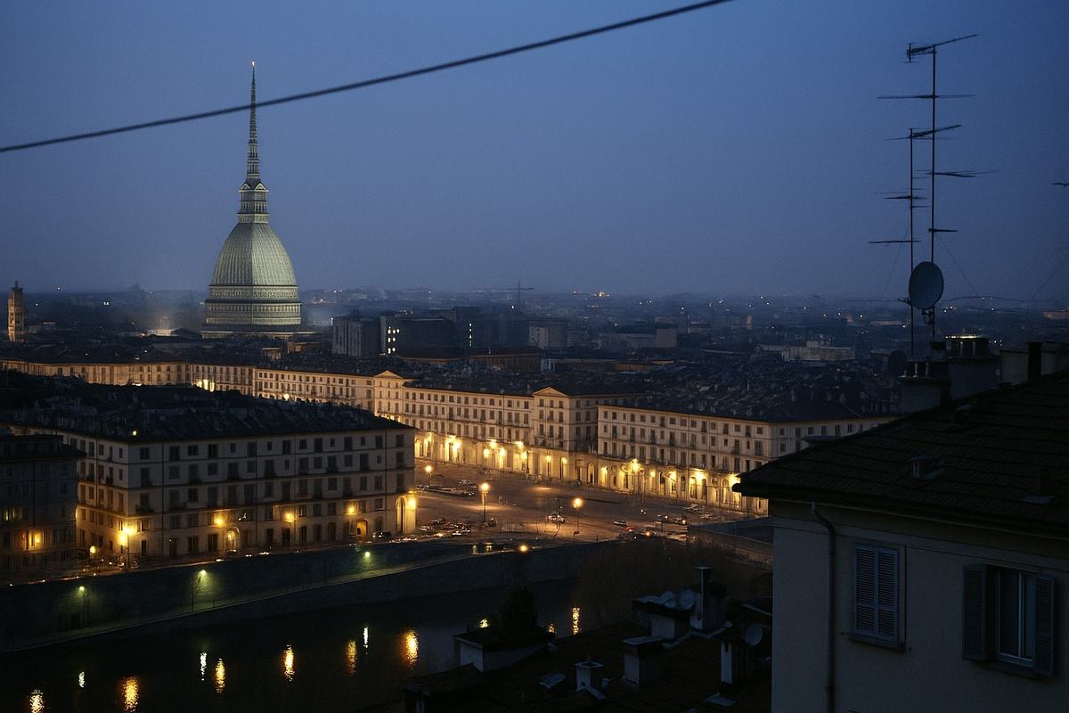Contemporary (2005) digital press photograph of Turin’s skyline at dusk, taken from a rooftop vantage near Monte dei Cappuccini; captured on a Canon EOS-1D Mark II with a 35mm equivalent focal length; cool blue hour tones with sodium-vapor streetlights creating warm pools, mild high-ISO noise in the shadows; asymmetric composition with the Mole Antonelliana off to the left third and the Lingotto rooftop test track faintly visible on the right horizon; tram wires, rooftop antennas, and a few cranes in the midground; light haze over the Po River, no legible signs or text.