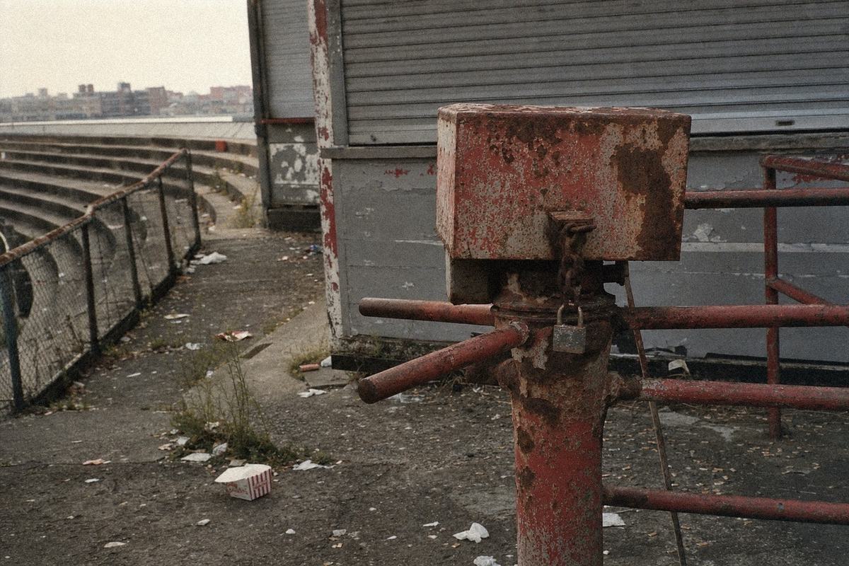Rusted turnstiles and a shuttered kiosk at the Mercator Ground, terraces empty under grey sky.