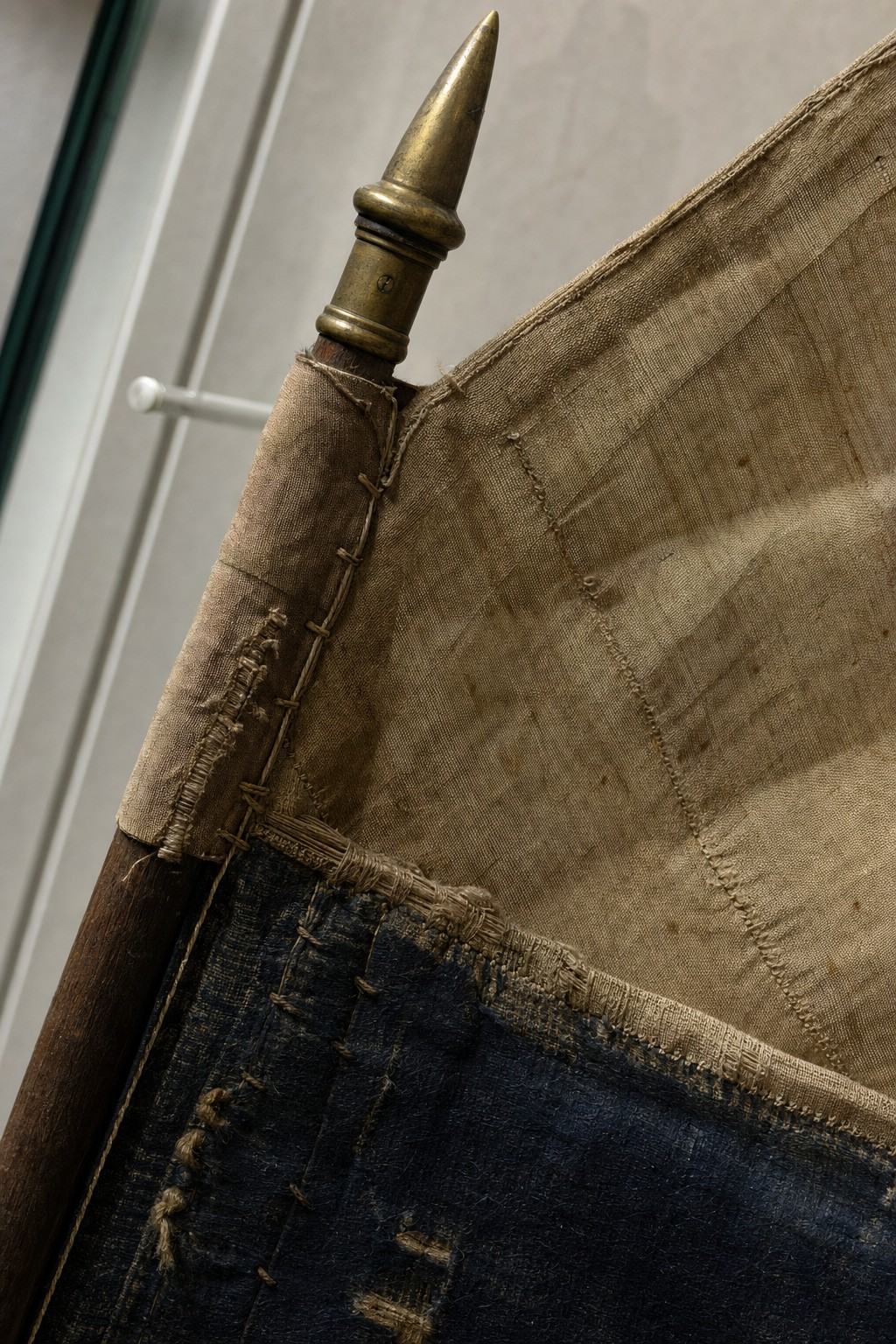 Detail van een Haarlemse schuttersbanier met gestopte zijde, zichtbare naden en patina op de spie, onder conserveringslicht.