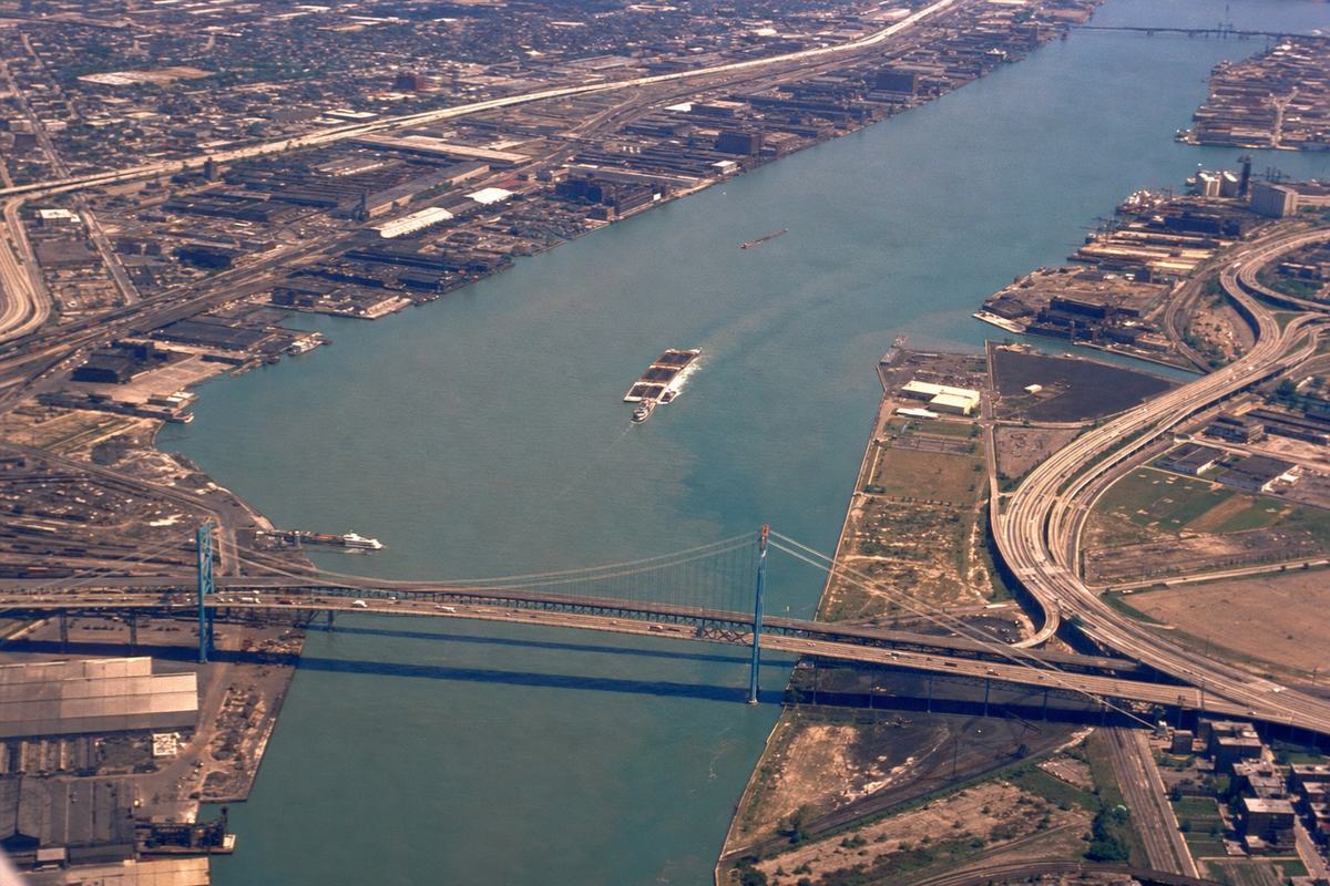 Late‑1960s Kodachrome aerial of Detroit–Windsor freeways and the continuous riverfront along the Detroit River.
